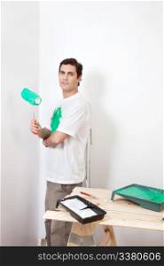Portrait of man holding paint roller at home