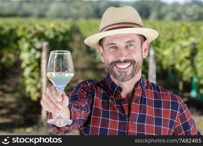 portrait of man holding wineglass forward at vineyard