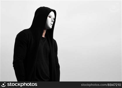 Portrait of man in black hoodie wearing white anonymous mask.. Portrait of man in black hoodie wearing white anonymous mask