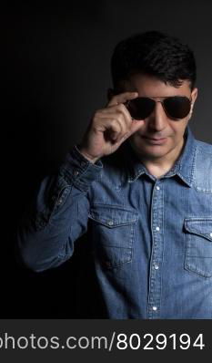 Portrait of man in Blue jean shirt with sunglasses on black background