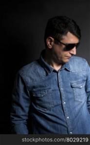 Portrait of man in Blue jean shirt with sunglasses on black background