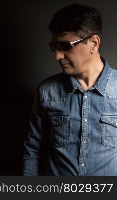 Portrait of man in Blue jean shirt with sunglasses on black background