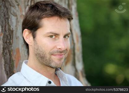 Portrait of man in front of tree trunk