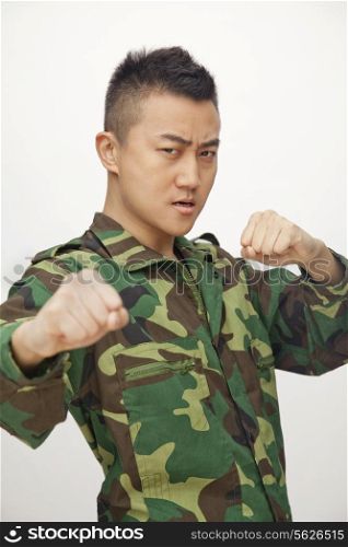 Portrait of man in military uniform putting up fists to fight