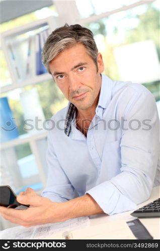 Portrait of man in office using calculator