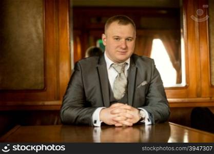 Portrait of man in suit sitting at old wooden table