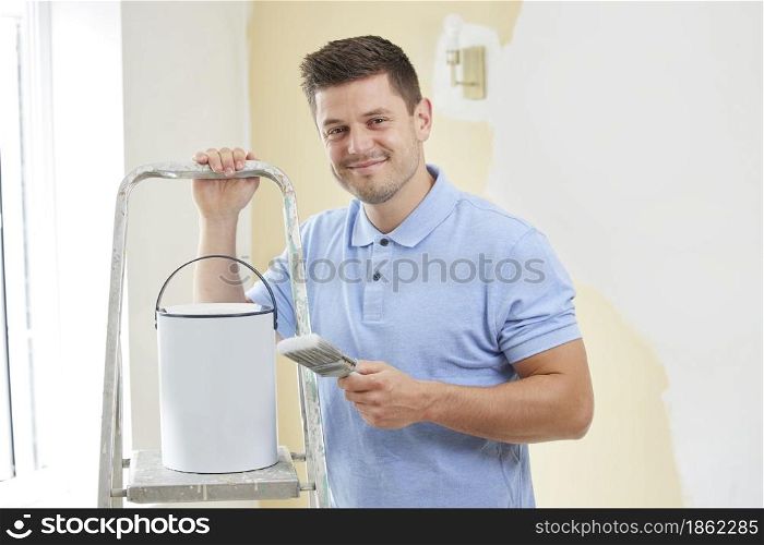 Portrait Of Man Painting Wall In Room Of House With Brush