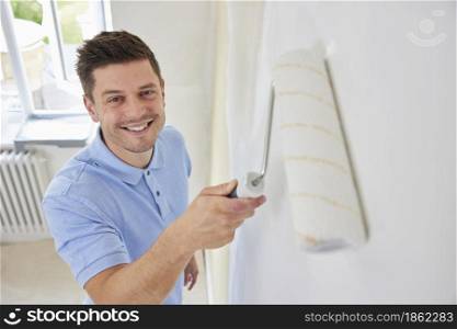 Portrait Of Man Painting Wall In Room Of House With Paint Roller