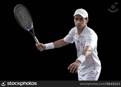 Portrait of man playing tennis against black background