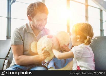 Portrait of man playing with her daughter while sitting and waiting for boarding in airport