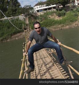 Portrait of man posing on bamboo bridge, Nam Khan river, Luang Prabang, Laos