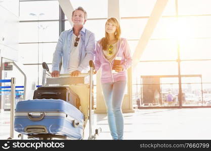 Portrait of man pushing baggage cart for check in with her daughter at airport