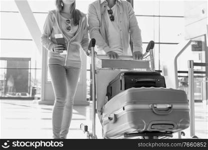 Portrait of man pushing baggage cart for check in with her daughter at airport