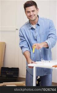 Portrait Of Man Putting Together Self Assembly Furniture At Home