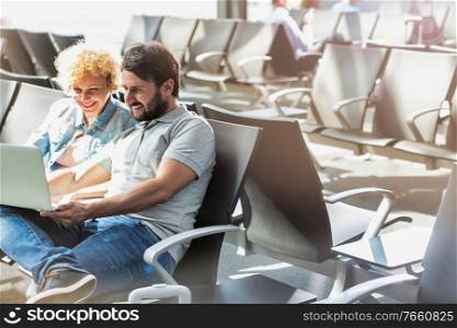 Portrait of man showing funny picture with his wife while waiting in airport