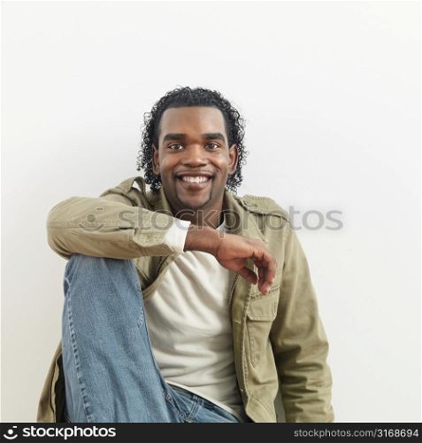 Portrait of man sitting against white background smiling.