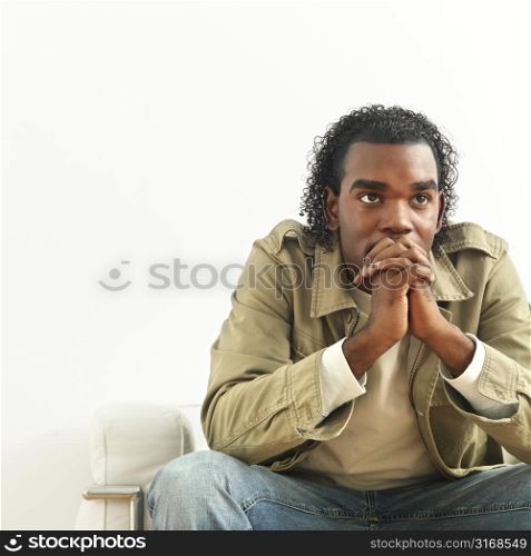 Portrait of man sitting with hands clasped as if in thought.