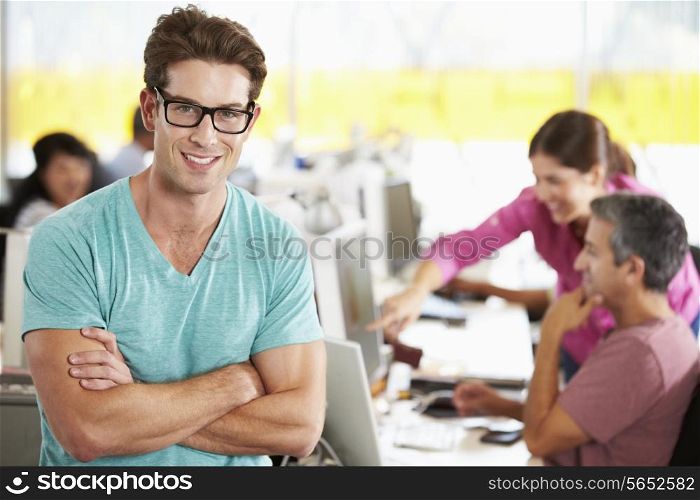 Portrait Of Man Standing In Busy Creative Office