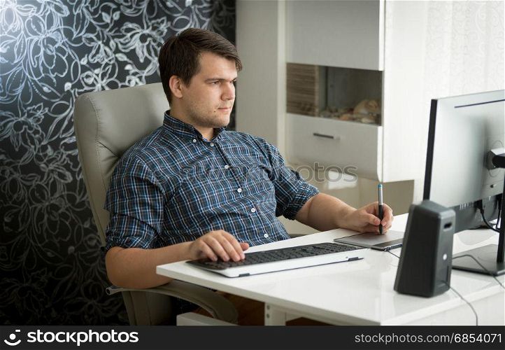 Portrait of man using digital graphic tablet and keyboard at office