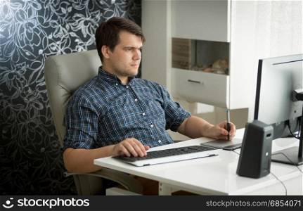 Portrait of man using digital graphic tablet and keyboard at office