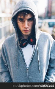 Portrait of man wearing hooded top and headphones looking at camera