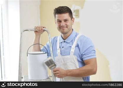 Portrait Of Man Wearing Overalls Painting Wall In Room Of House With Brush