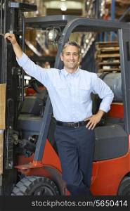 Portrait Of Man With Fork Lift Truck In Warehouse