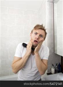 Portrait of man with hairbrush grimacing in bathroom