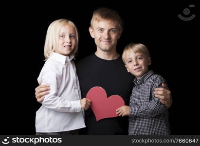 Portrait of man with son and daughter holding heart shaped paper 