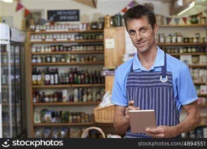 Portrait Of Man Working In Delicatessen Using Digital Tablet