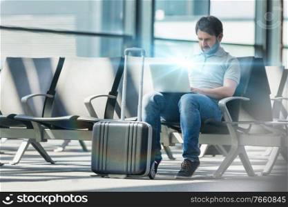 Portrait of man working with his laptop while waiting for boarding in airport