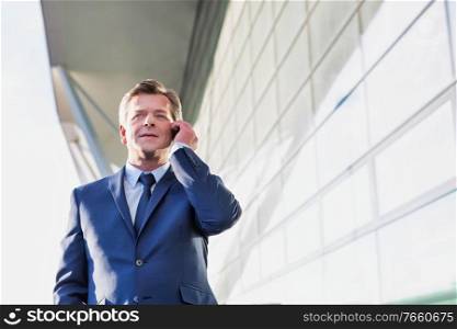 Portrait of mature attractive businessman talking on smartphone while standing at Gdansk Airport