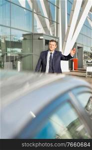 Portrait of mature businessman calling taxi in the airport