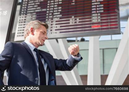 Portrait of mature businessman checking time on his watch while waiting in the airport