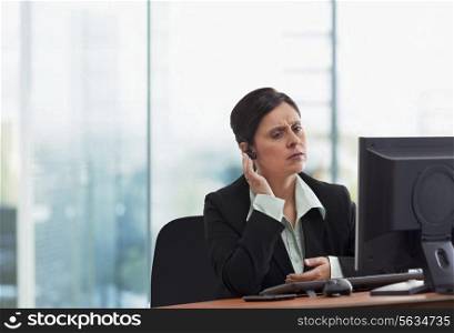 Portrait of mature businesswoman on call while looking at computer