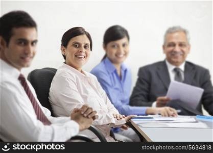 Portrait of mature businesswoman smiling with other executives