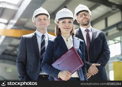 Portrait of mature businesswoman with male colleagues in metal industry