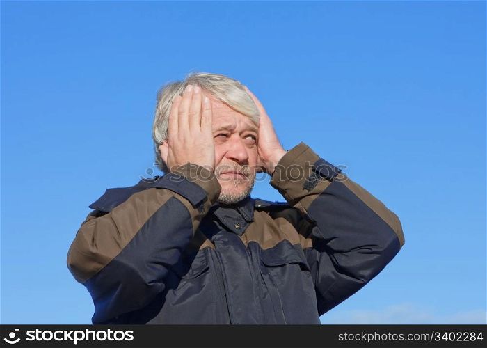 Portrait of mature concerned man with grey hair on blue sky of the background.