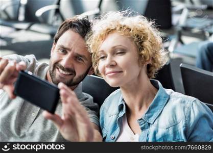 Portrait of mature couple taking selfie while waiting for boarding in airport
