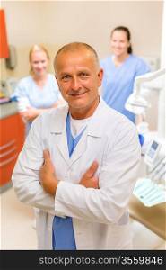 Portrait of mature dentist man with team in stomatology clinic