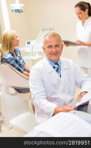 Portrait of mature dentist surgeon at dental office with patient