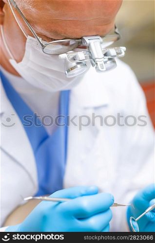 Portrait of mature dentist surgeon holding dental tools wear mask