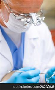 Portrait of mature dentist surgeon holding dental tools wear mask