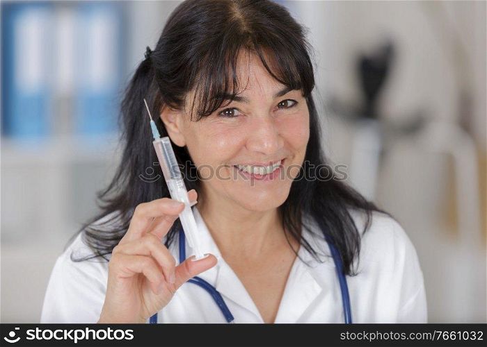 portrait of mature doctor holding injection