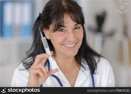 portrait of mature doctor holding injection