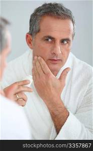 Portrait of mature man applying moisturizer on his face