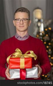 Portrait of mature man holding stack of Christmas presents