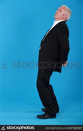 portrait of mature man standing back in profile against blue background