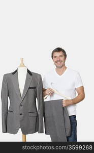 Portrait of mature man standing next to tailor&acute;s dummy over gray background