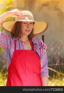 Portrait of mature smiling woman wearing big straw hat in garden